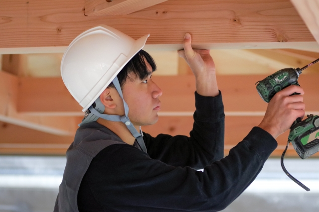 躯体にドリルで穴をあけている大工