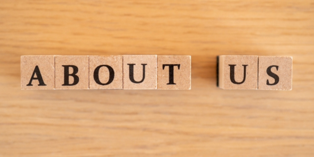 木製の背景の上に「ABOUT US」と書かれたブロックが並べられている画像