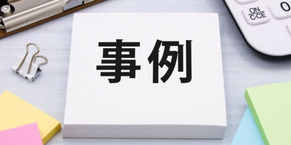「事例」と書かれた白い紙がクリップや付箋とともにデスク上に置かれている画像
