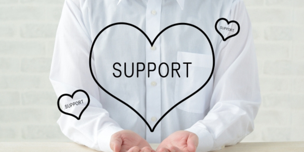 白いシャツを着た人物が手を広げ、中央に「SUPPORT」と書かれたハートのイラストが重ねられている画像