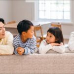 ソファに寄りかかりながら笑顔で会話を楽しむ幸せそうな日本人の家族
