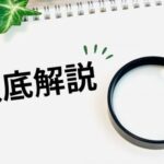メモ帳に書かれた「徹底解説」の文字と拡大鏡、周囲を彩る緑の植物