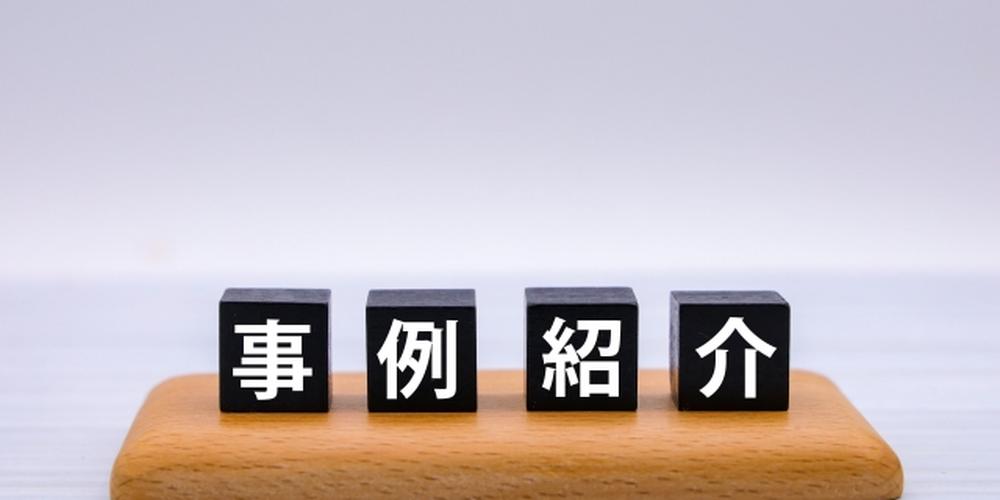 「事例紹介」と書かれた黒いブロックが木の台に並べられたシンプルな構成。実績や成功事例を紹介するイメージ。