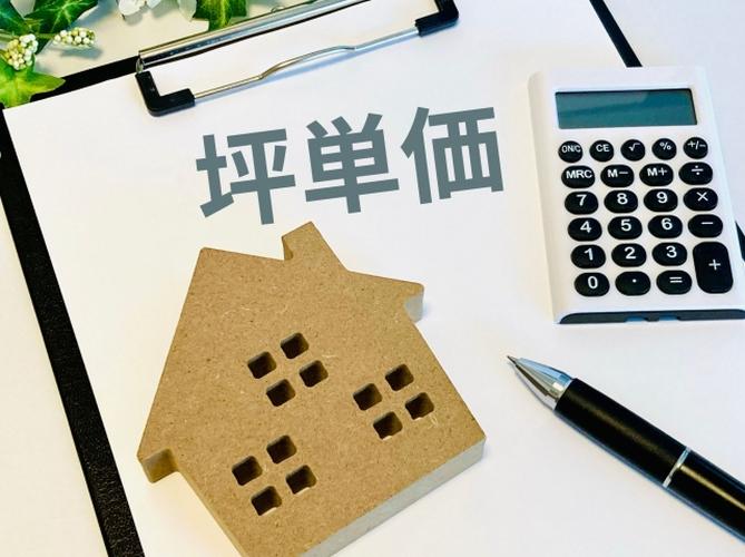 坪単価と書かれた書類の上に置かれた木製の家の模型、電卓とペンが並ぶ住宅価格計算のイメージ