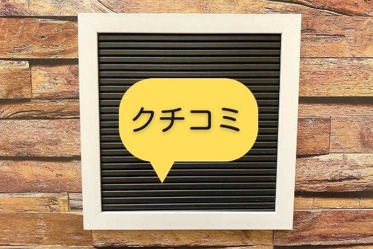 「クチコミ」と書かれた吹き出しが掲示されたボードと木目の背景によるレビュー・評判のイメージ写真
