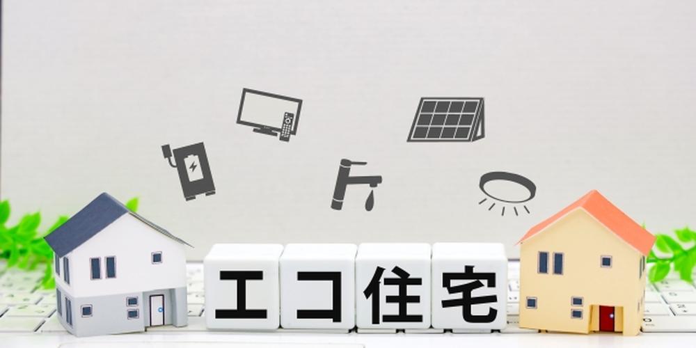 エコ住宅と書かれたキューブブロックと2軒の住宅模型。太陽光パネルや省エネ設備のアイコンが配置された環境配慮型住宅のイメージ。