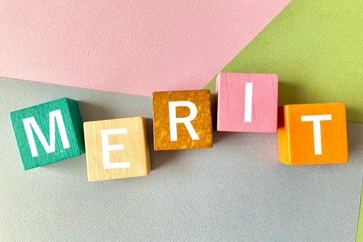 カラフルな背景に「MERIT」と書かれた木製ブロックが並ぶ、利点やメリットを表現したイメージ