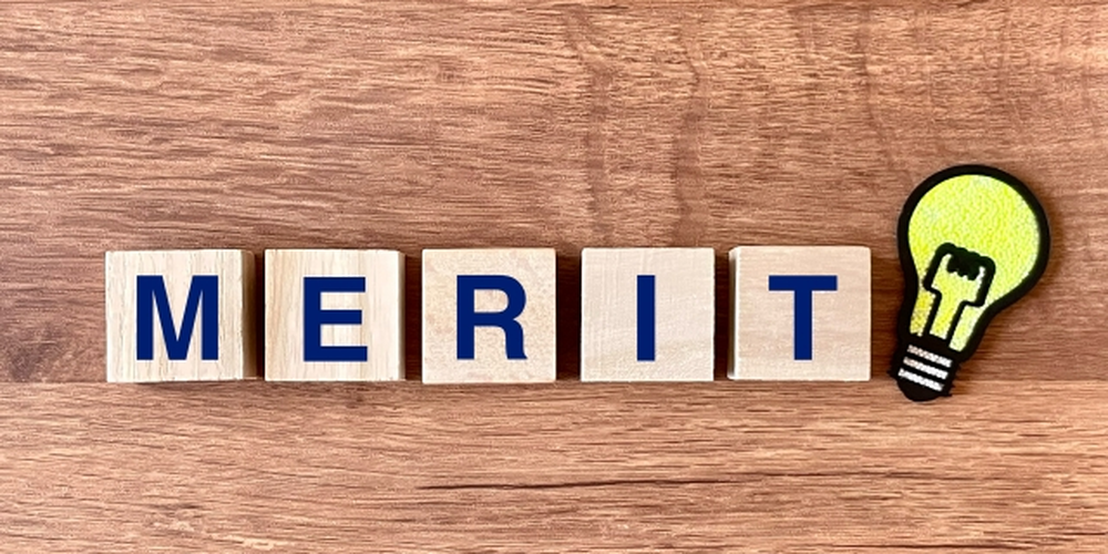 「MERIT」の文字と電球アイコンが並ぶ、利点や強みを表現した木目背景のイメージ