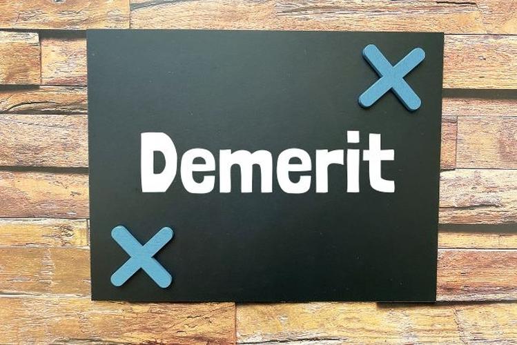 木目の背景に「Demerit」と書かれた黒いボードとバツ印が添えられた、欠点や注意点のイメージ