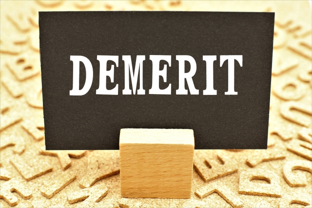「MERIT」の文字と電球アイコンが並ぶ、利点や強みを表現した木目背景のイメージ