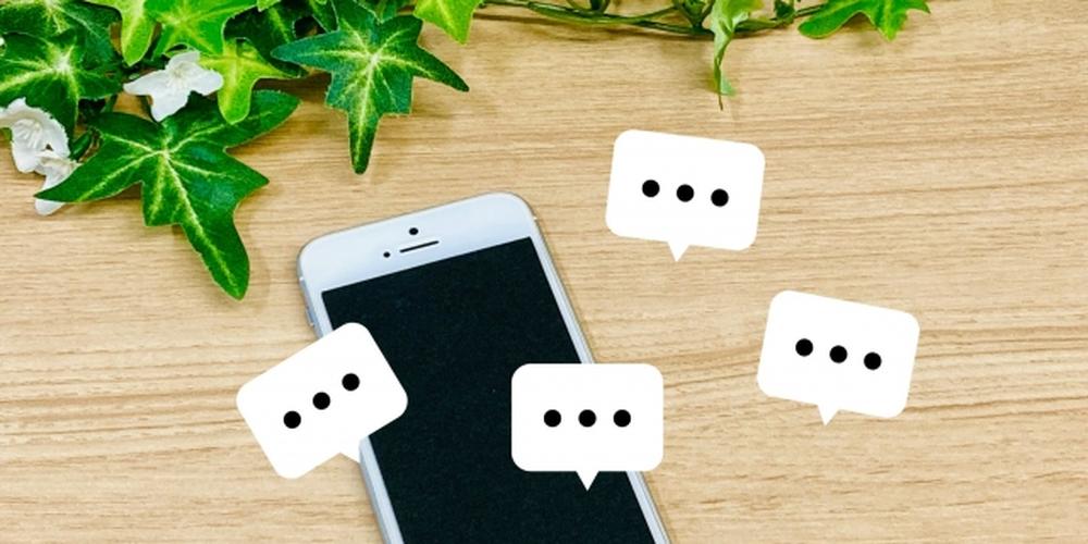 スマートフォンと吹き出しアイコン、背景にアイビーがあしらわれたチャットイメージ写真