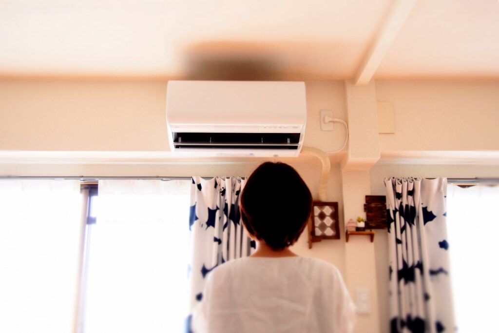 エアコンを見上げる人を背後から見ている画像