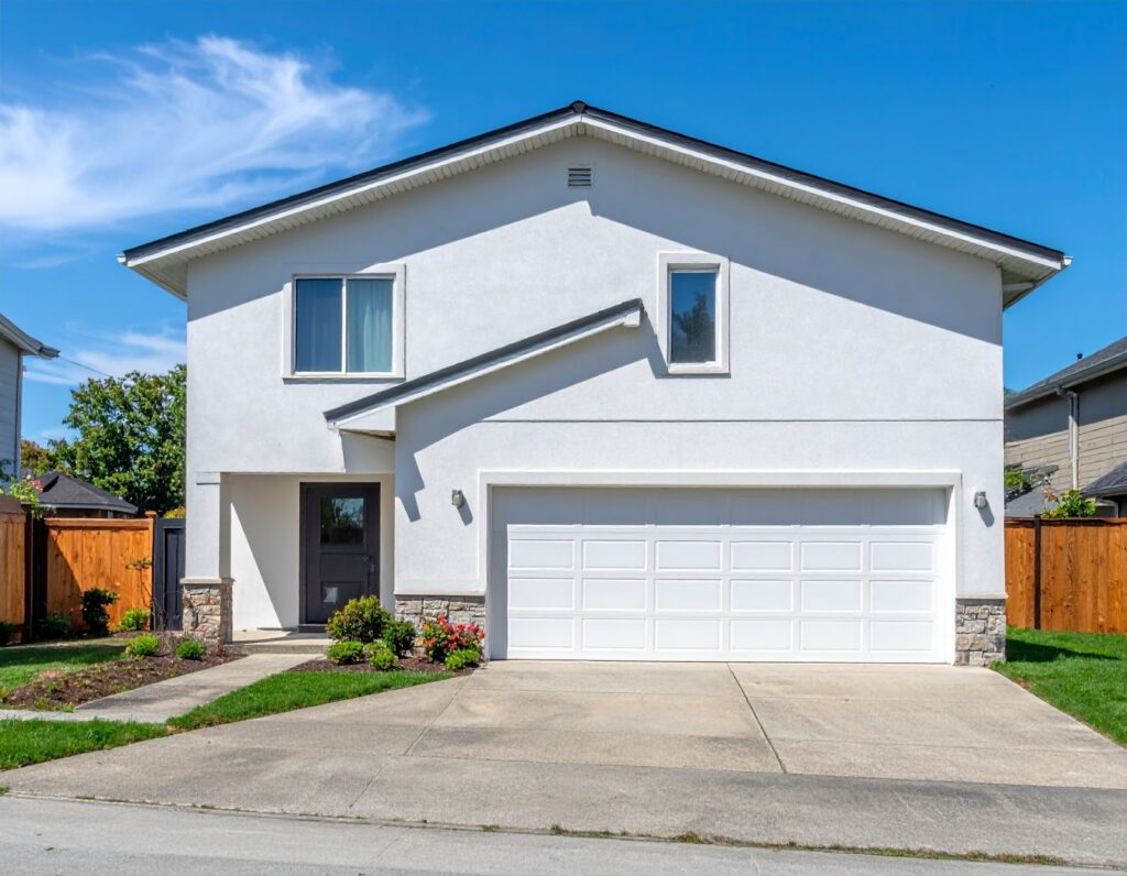 白い壁に黒い屋根が特徴的な一軒家と青空の画像