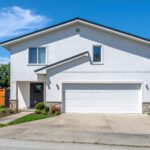 白い壁に黒い屋根が特徴的な一軒家と青空の画像